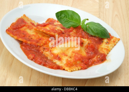 Käse-gefüllte Ravioli Pasta in eine rote Tomatensauce mit Basilikum Blätter Beilage. Stockfoto