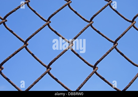 Detail von einem rostigen Maschendrahtzaun mit blauem Himmelshintergrund Stockfoto