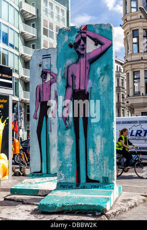 Bilder von Männern auf bunten Stücke der Berliner Mauer am Checkpoint Charlie Border post, Cheeseburger, Berlin Stockfoto