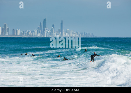 Surfer auf einer Welle mit Surfers Paradise Skyline im Hintergrund. Burleigh Heads, Gold Coast, Queensland, Australien Stockfoto