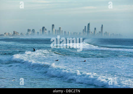 Surfer in Morgen Schwellen mit Surfers Paradise Skyline im Hintergrund. Burleigh Heads, Gold Coast, Queensland, Australien Stockfoto