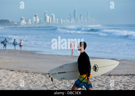 Surfer am Strand von Burleigh Heads mit Surfers Paradise Skyline im Hintergrund. Burley Heads, Gold Coast, Queensland, Australien Stockfoto