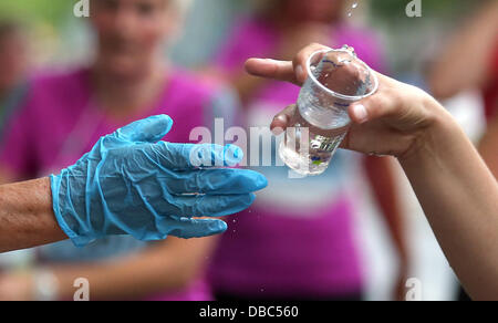 Die Teilnehmer des 22. Vattenfall City-Nacht erhalten Wasser während der fünf Kilometer lange Fahrt entlang der Kurfürstendamm bei Temperaturen um 30 Grad Celsius in Berlin, Deutschland, 27. Juli 2013. Foto: Wolfgang Kumm Stockfoto