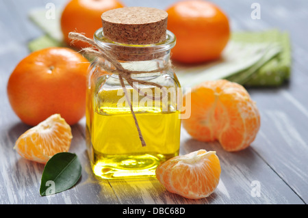 Mandarinen Öl in eine Glasflasche mit frischen Mandarinen он hölzernen Hintergrund Stockfoto