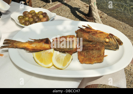 Restaurant am Wasser mit Kabeljau in Mehl gebraten und in Olivenöl mit Zitrone und Gericht von Oliven in Gikes, Peloponnes, Griechenland gekocht Stockfoto