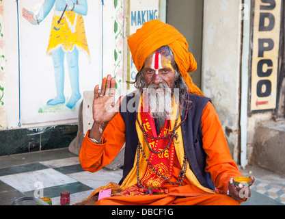 Ein älterer bärtiger Hindu Sadhu, heiliger Mann, in traditionellen bunten Safran Roben, einen Segen in Udaipur, Indien im Gegenzug für Almosen geben Stockfoto