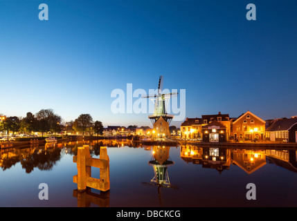 Landmark Windmühle De Adriaan in Haarlem Holland, Niederlande. Am Fluss Spaarne Kanal mit Restaurant Zuidam in der Abenddämmerung Stockfoto