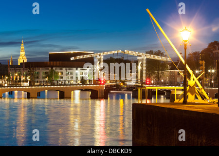 Amsterdam Amstel Fluss mit Skinny Bridge, Magere Brug, Opernhaus und Zuiderkerk in der Dämmerung, Nacht, Abend im Sommer. Stockfoto