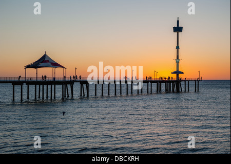 Menschen auf der Mole bei Sonnenuntergang am Strand von Adelaide Brighton Stockfoto