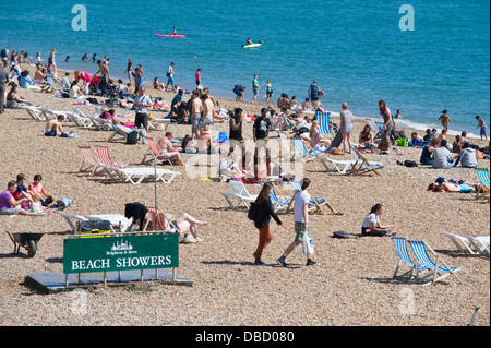 Urlauber entspannen Sie im Sonnenschein am Strand von Brighton East Sussex England UK Stockfoto