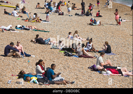 Urlauber entspannen Sie im Sonnenschein am Strand von Brighton East Sussex England UK Stockfoto