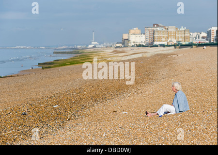 Ältere Frau sitzt alleine am Strand im frühen Morgen in Brighton East Sussex England UK Stockfoto