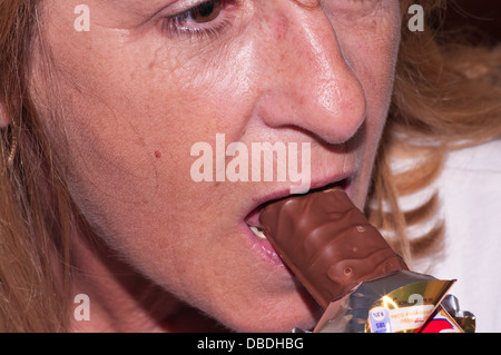 Nahaufnahme einer mittlere gealterte Frau essen Schokolade Stockfoto