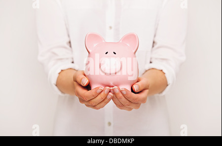 Frau hält ein Sparschwein mit beiden Händen Stockfoto