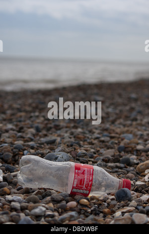 Wurf auf den felsigen Stein Strand zeigen, dass eine leere Coca Colaflasche verworfen. Stockfoto