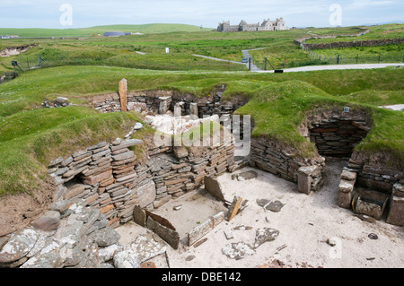 Haus 5 in Skara Brae neolithischen Dorf auf Orkney Festland mit Skaill House im Hintergrund. Stockfoto