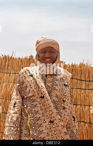 Junge malische Dorf Mann aus Nord-Ost-Mali in traditioneller Kleidung vor Holz gerahmt gewebte Matten Hütte, Westafrika Stockfoto