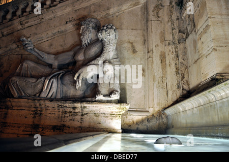 Römische Darstellung des Tiber als Gott (Tiberinus) mit Füllhorn an der Campidoglio neben einem beleuchteten Brunnen in Rom. Stockfoto