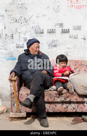 Qijiawan, Nanjing, China. Großvater und Enkelin sitzt auf einer Couch auf der Straße. Stockfoto