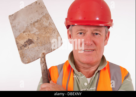 Lächelnde Builder tragen einen roten Schutzhelm und eine Schaufel über der Schulter tragen. Stockfoto