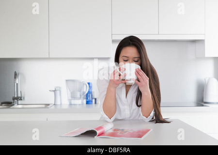 Gemischte Rassen Frau liest Magazin in Küche Stockfoto