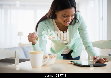 Gemischte Rassen Frau mit Tablet-PC zum Frühstück Stockfoto