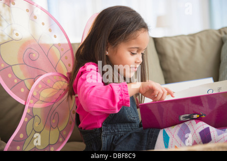 Hispanischen Mädchen tragen Feenflügel auf sofa Stockfoto