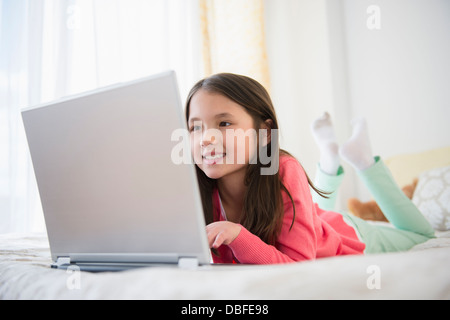 Gemischte Rassen Mädchen mit Laptop am Bett Stockfoto