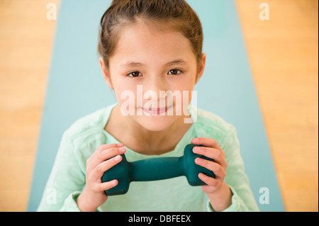 Gemischte Rassen Mädchen halten Gewicht auf Yoga-Matte Stockfoto