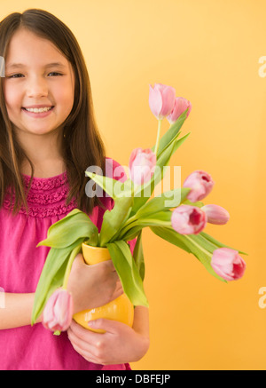 Gemischte Rassen Mädchen halten Vase mit Blumen Stockfoto