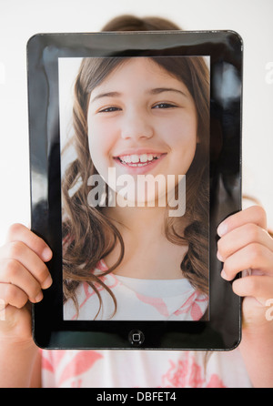 Hispanischen Mädchen Holding Tablet mit Bild ihres Gesichts Stockfoto