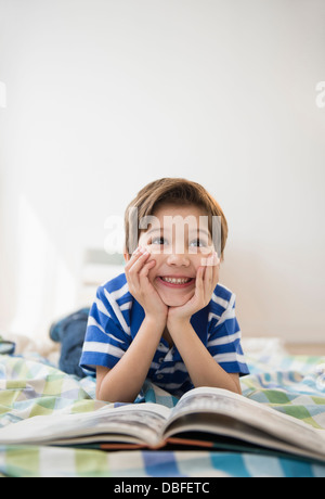 Hispanische Junge liest am Bett Stockfoto