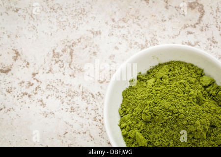 Moringa Blattpulver in einer kleinen Schüssel gegen eine keramische Fliese Hintergrund mit einem Textfreiraum Stockfoto