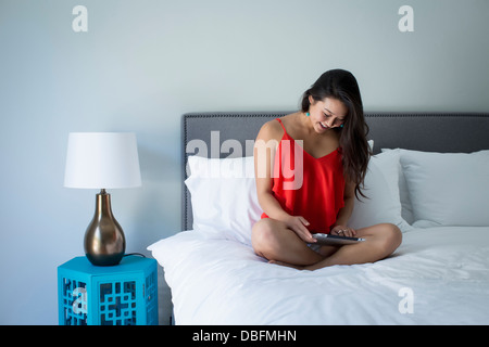 Japanerin mit Tablet-PC auf Bett Stockfoto