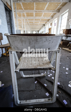 Verlassene Fabrik mit gebrochenen Stoffe auf dem Boden wie Stühle und Holzplatten. niemand. Konzentrierte sich auf den Vordergrund mit einem schmutzigen Stockfoto