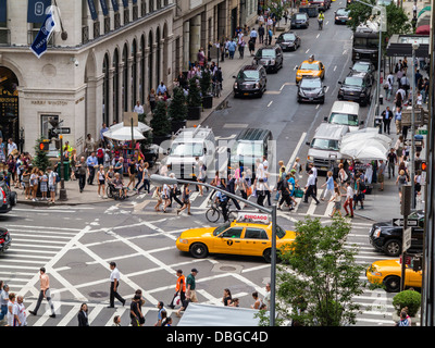Geschäftige Kreuzung in Manhattan, New York Street - Menschen und Verkehr an einer Autobahnkreuzung an der Ecke der 5th Avenue im Sommer Stockfoto