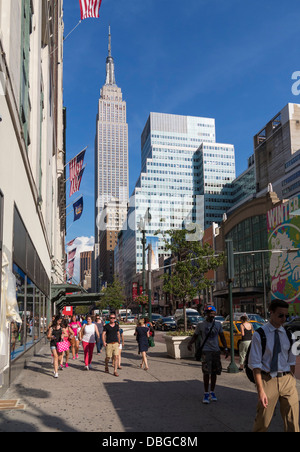 New Yorker Street - New Yorker auf dem Bürgersteig mit Empire State Building im Hintergrund, Manhattan, New York City im Sommer Stockfoto