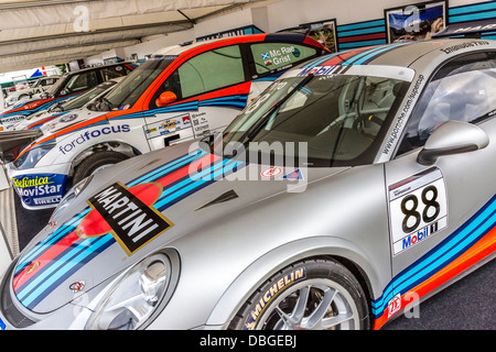 Fahrerlager auf dem 2013 Goodwood Festival of Speed, Martini Racing feiert. Mit Porsche und Ford Autos im Vordergrund. Stockfoto