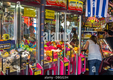 Arcade mit Klaue Kran Spielautomaten gefüllt mit Spielzeug und Münze Drücker / push Medaille Spiele bei Reisen Kirmes / Karneval Stockfoto