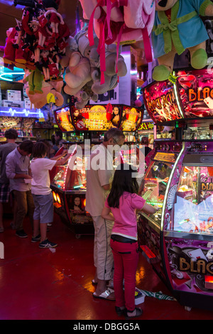 Vater mit Mädchen spielen mit Münze Drücker / push-Medaille Spiel in der Spielhalle auf Reisen Jahrmarkt / Kirmes Reisen Stockfoto