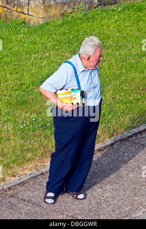 Overhead Rückansicht der ältere Mann mit Bier zu Fuß entlang der Fahrbahn - Frankreich. Stockfoto