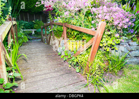 Typische englische Garten Pflanzen Blumen umgeben Holzbrücke Stockfoto