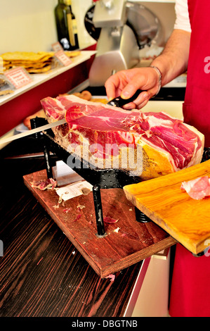 Schinken (Schinken crudo in Italienisch) oder Prosciutto di Parma trocken geheilt wird aus dem Knochen in einem Feinkostgeschäft in der Toskana Italien geschnitten Stockfoto