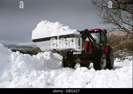 Clearing Landstraße mit Traktor und Lader nach Schneesturm es blockiert hat. Cumbria, UK. Stockfoto