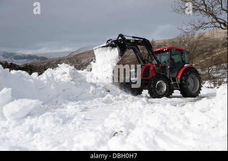 Clearing Landstraße mit Traktor und Lader nach Schneesturm es blockiert hat. Cumbria, UK. Stockfoto