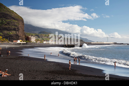 Puerto de Tazacorte mit Touristen Sonnenbaden am dunklen Strand und hohe Wellen. Stockfoto