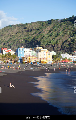 Bunte Puerto de Tazacorte mit Touristen am dunklen Strand Sonnenbaden. Stockfoto