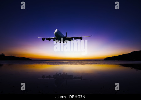 Flugzeug fliegen auf bunten tropischen Abendhimmel über dem Meer bei Sonnenuntergang mit Reflexion Stockfoto