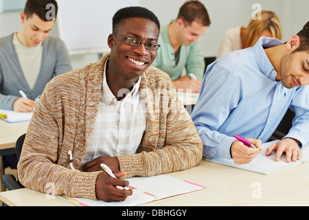 Glücklich lächelnde afrikanische Student Notizen in Universität Klasse Stockfoto