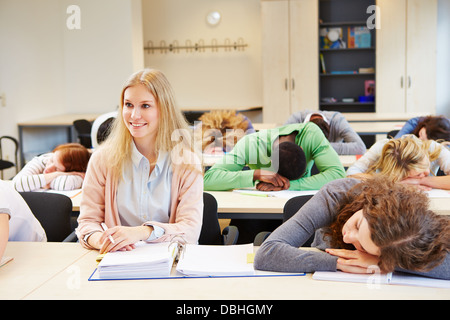 Studenten schlafen in Schule Klasse und junge Frau hält wach Stockfoto